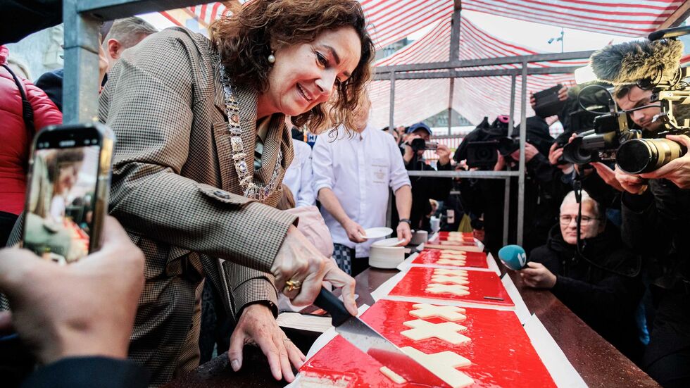 Amsterdams Bürgermeisterin Femke Halsema schneidet die lange Torte an. 