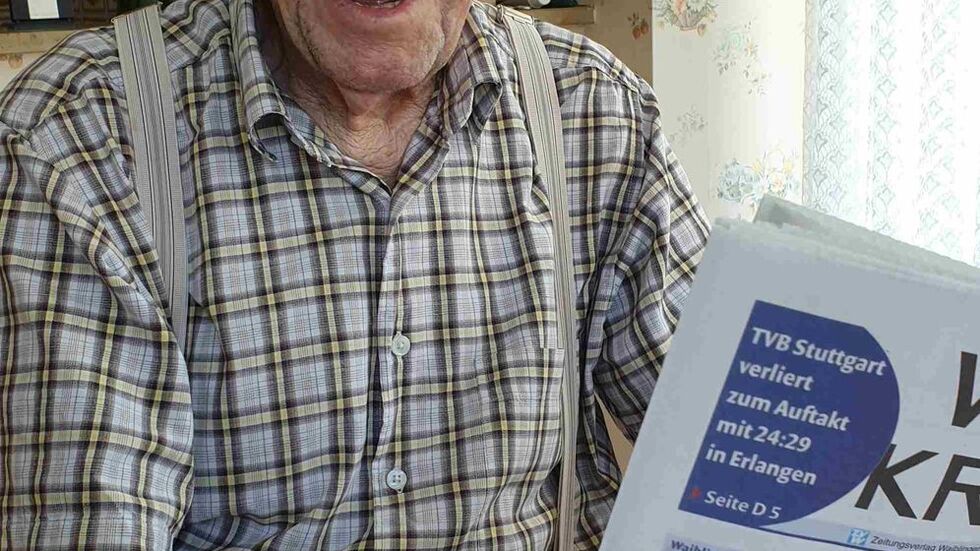 Karl Haidle sitzt an seinem 104. Geburtstag an einem Tisch und liest Zeitung.