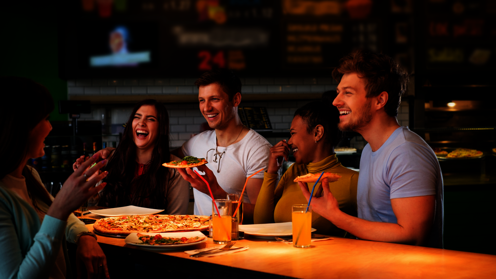Fünf Freunde essen in einem Restaurant eine Pizza.
