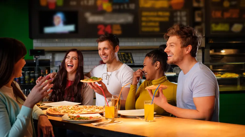 Fünf Freunde essen in einem Restaurant eine Pizza.