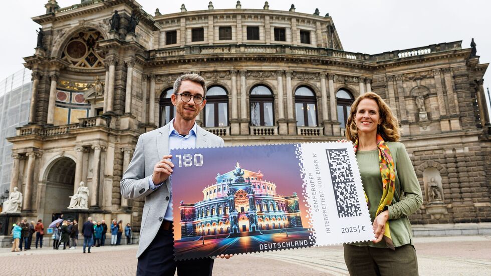 Semperoper-Intendantin Nora Schmid (re.) zeigt mit Benjamin Löwen von der Deutschen Post die neue Briefmarke auf dem Theaterplatz