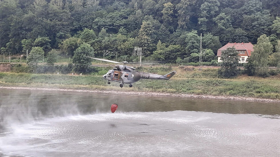 Ein Hubschrauber nimmt Wasser in der Elbe auf 