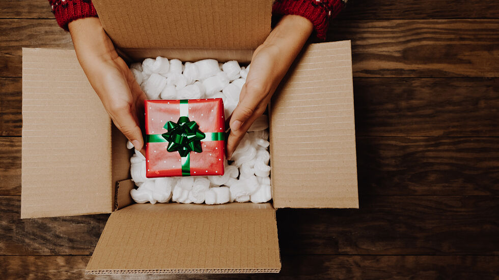 Wo bleibt mein Paket? Ausgerechnet zur Weihnachtszeit haben Planenschnitzer Päckchen geklaut. (Symbolbild) Eine Frau hält ein Paket mit einem Geschenk.