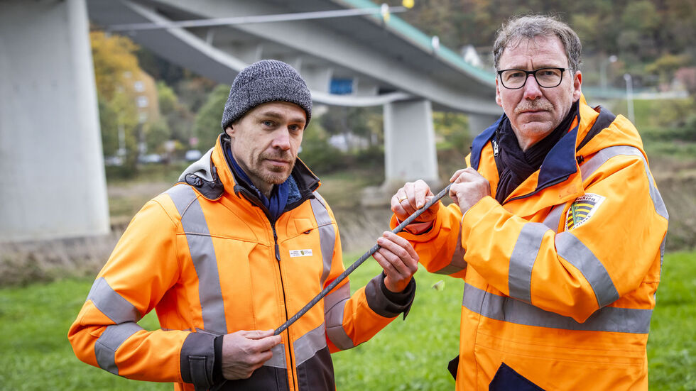 Stephan Berger (re.) zeigt vor der Bad Schandauer Brücke eine marode Stahllitze