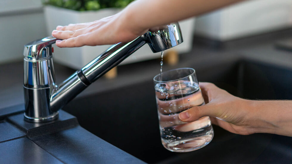 Eine Person holt sich Trinkwasser aus einem Wasserhahn.