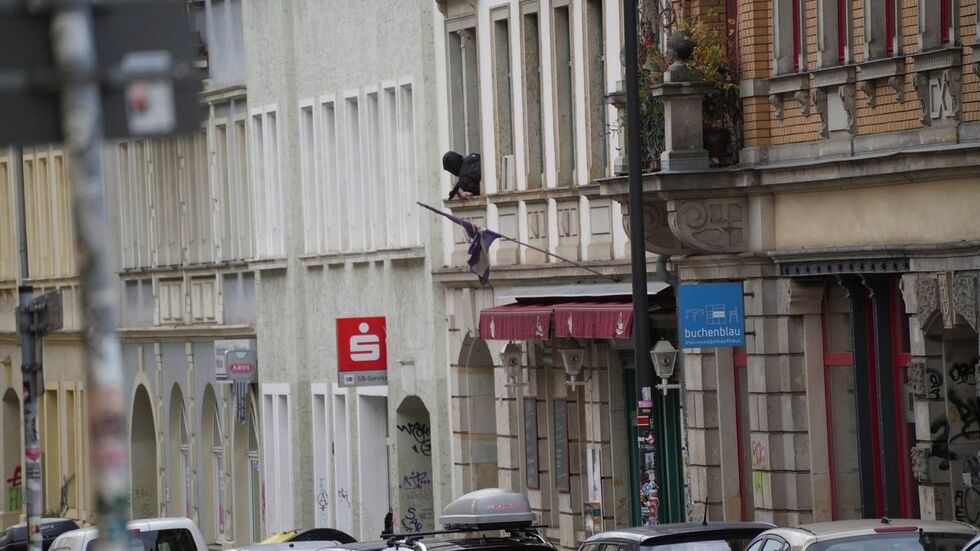 Der Mann beugt sich aus einem Fenster im ersten Stock 