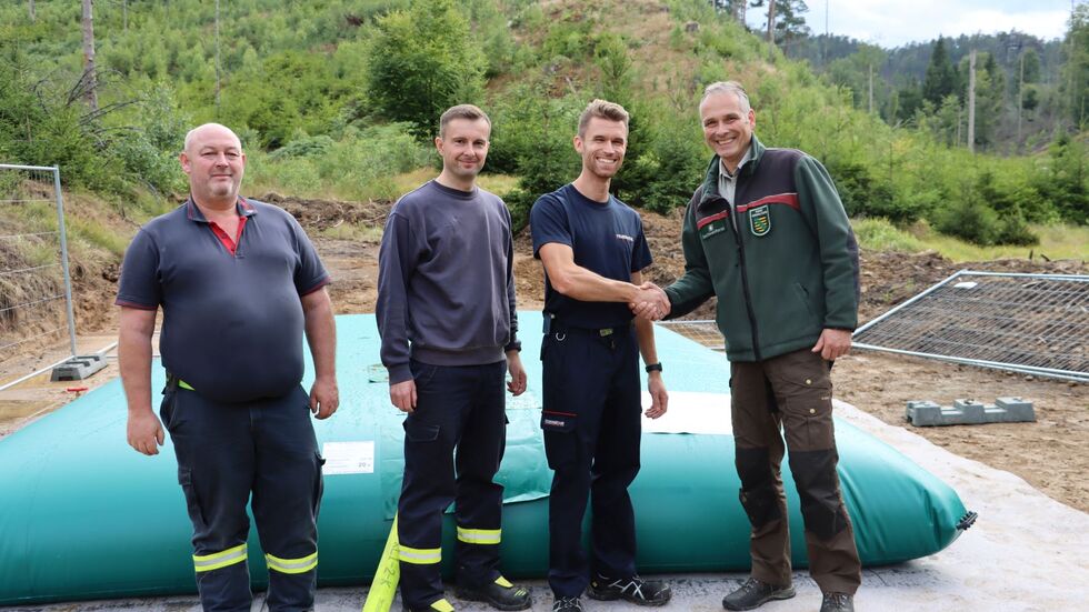 Der Leiter der Nationalparkverwaltung, Uwe Borrmeister (re) dankt Kevin Henker von der Feuerwehr Sebnitz und seinen Kollegen. 