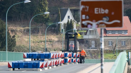 Mitarbeiter des Landesamts für Straßenbau und Verkehr (LASuV) platzieren im Rahmen des Belastungstests mit einem Gabelstapler Gewichte auf der gesperrten Elbbrücke.