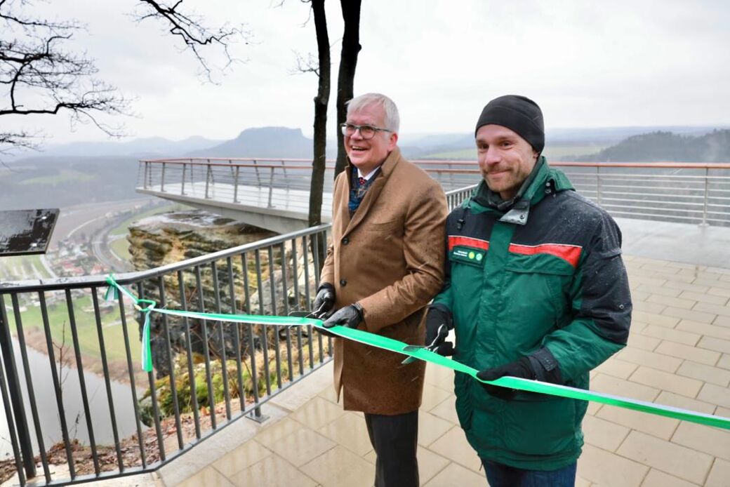 Finanzminister Hartmut Vorjohann schneidet zusammen mit Christian Starke vom Nationalpark Sächsische Schweiz das Band durch