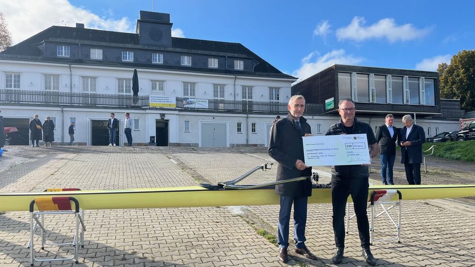 Innenminister Armin Schuster (li.) übergab Dresdens Sportbürgermeister Jan Donhauser den Förder-Scheck, mit dem das Bootshaus (im Hintergrund) saniert werden soll
