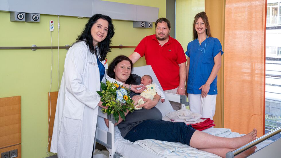 Prof. Pauline Wimberger (l.), Direktorin der Klinik für Frauenheilkunde und Geburtshilfe, und Aileen Raddatz, Stationsleiterin der GYN S1, gratulieren Sandra und Daniel zu ihrem Sohn Stanley-Daniel.