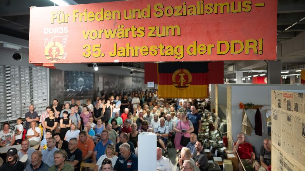 Teilnehmer stehen und sitzen während einer Versteigerung in den Ausstellungsräumen des bereits geschlossenen Museums „Welt der DDR“ in Dresden.